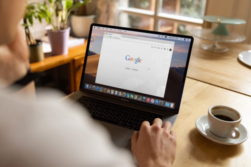 Man sitting at a desk looking at Google on a laptop