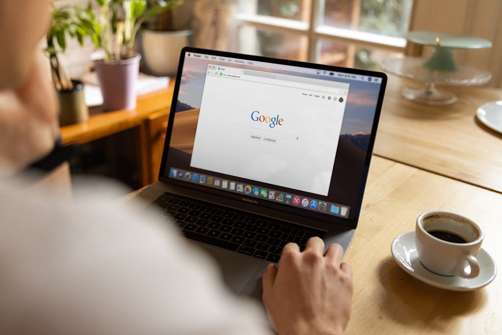 Man sitting at a desk looking at Google on a laptop