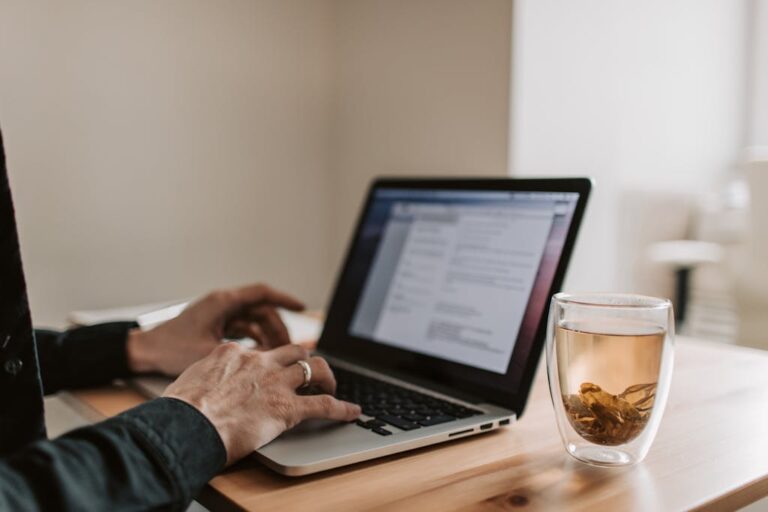Man typing on a laptop on a wooden desk