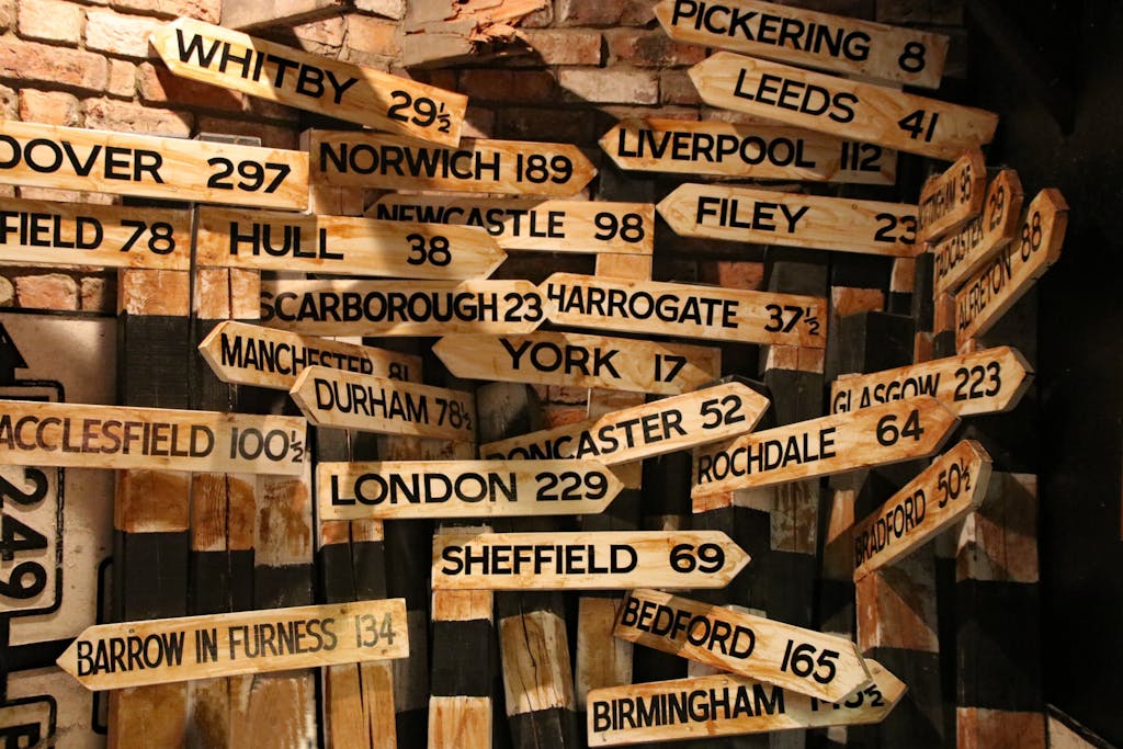 Brown wooden signage pointing to locations in the UK